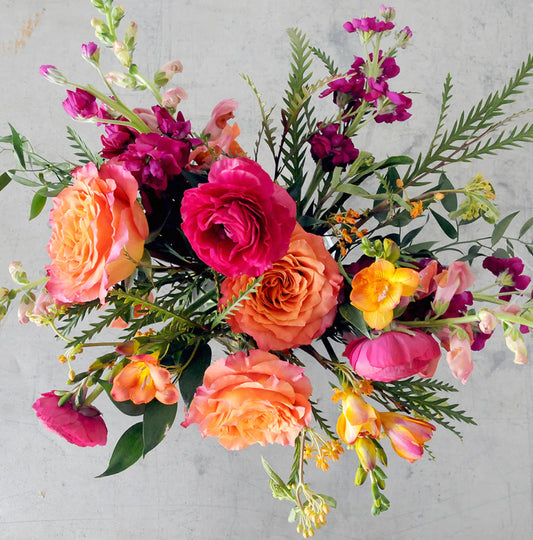 Fun colourful bouquet with bright pink, orange, fuchsia, and yellow flowers.